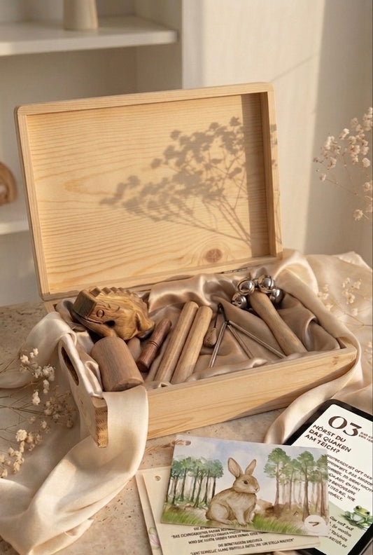 Geöffnete Montessori Klangbildbox mit hochwertigen Holz-Musikinstrumenten und Übungskarten für Kleinkinder